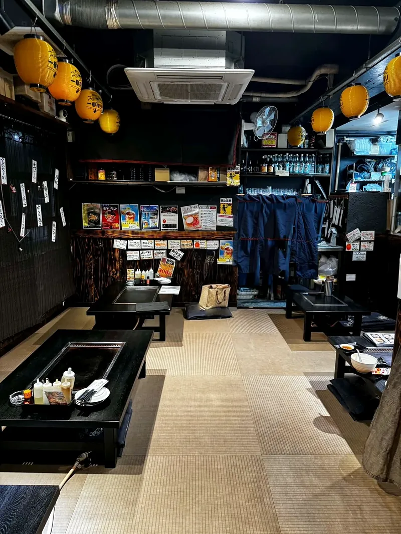 兎の花の座敷。天井から黄色いちょうちんが下がり、鉄板のついた黒いテーブルが並んでいる